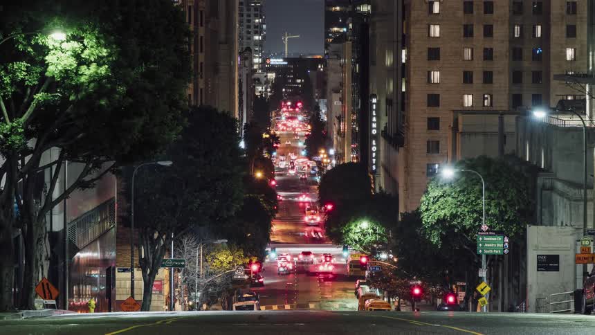 Traffic is flowing along a city street throughout the night