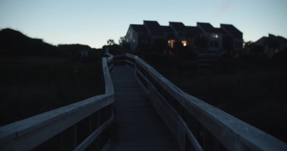 A person walks on a wooden walkway at dusk