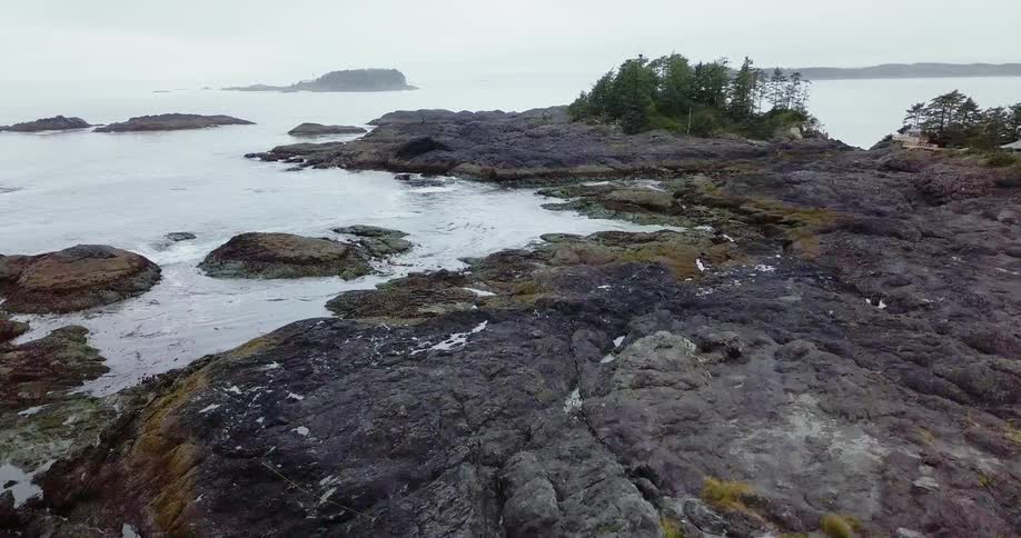 The tide flows towards the rocky shore