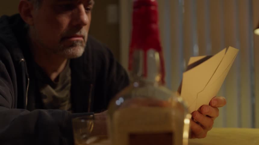 A man sits at a table reading mail