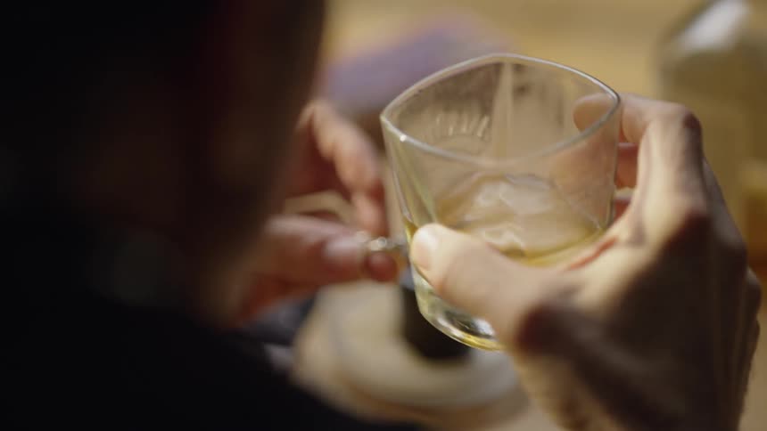 Man drinks whiskey while holding wedding rings