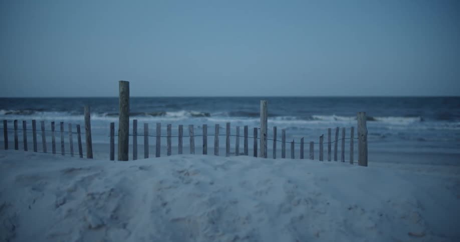 Waves are rolling onto a beach at dusk