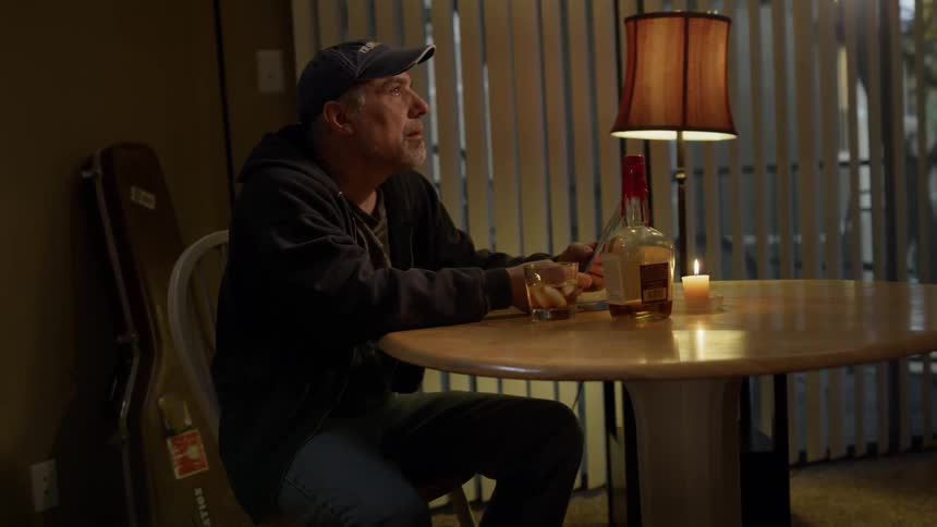 Man looks at photographs and drinks whiskey