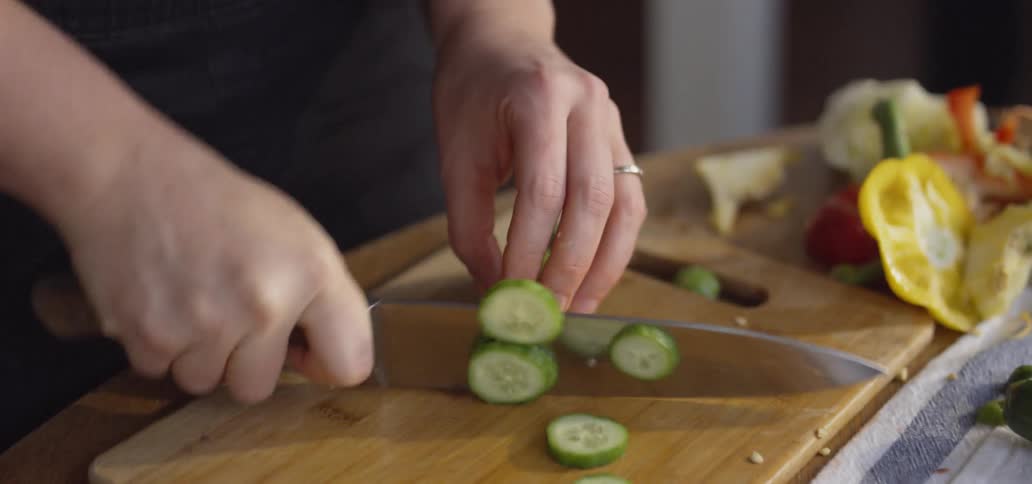 Man dices a cucumber on a cutting board