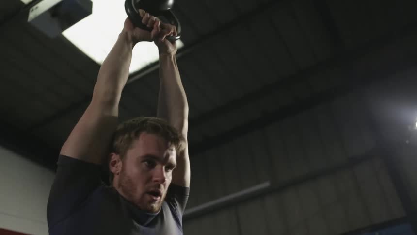 Man tossing a kettle bell above his head repeatedly