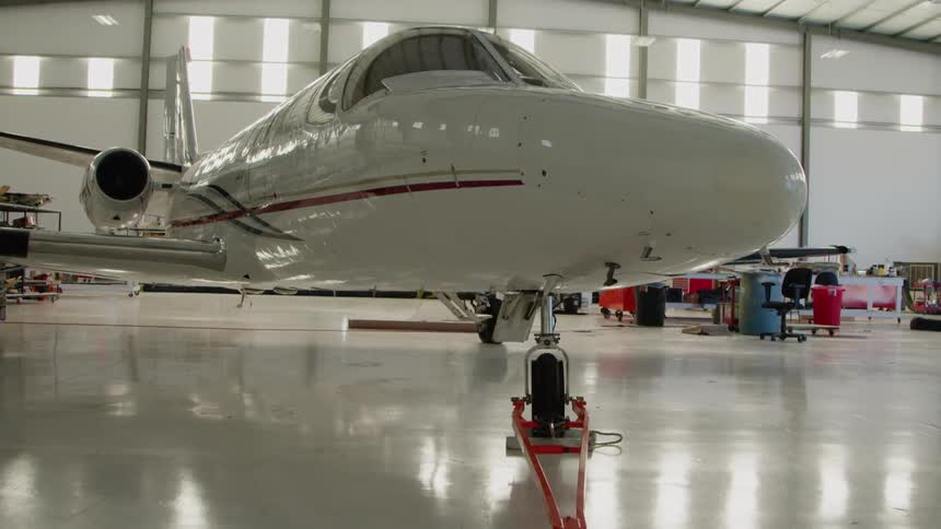 The white plane sits in the bright hangar