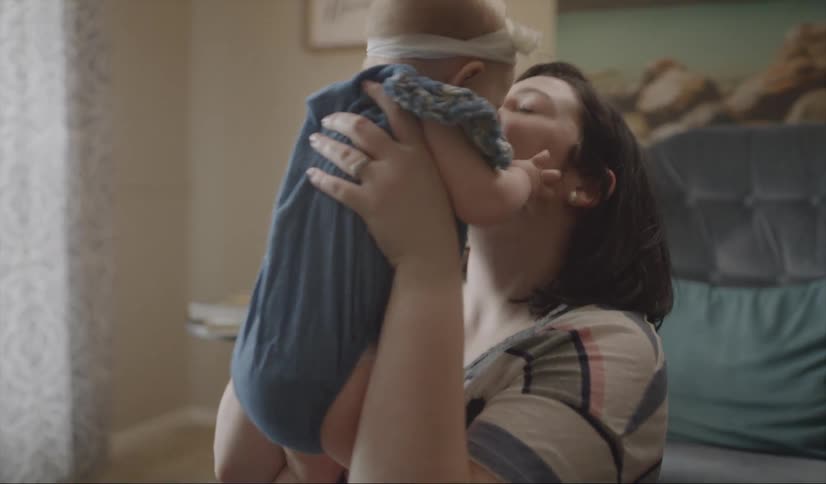 A woman bounces a baby and smiles