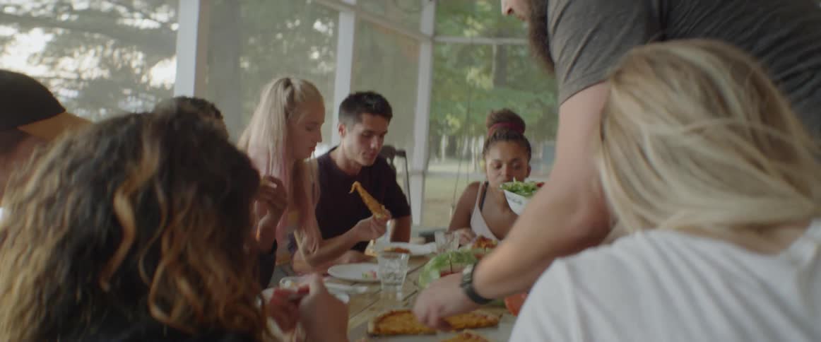 Friends eat pizza on a screened patio