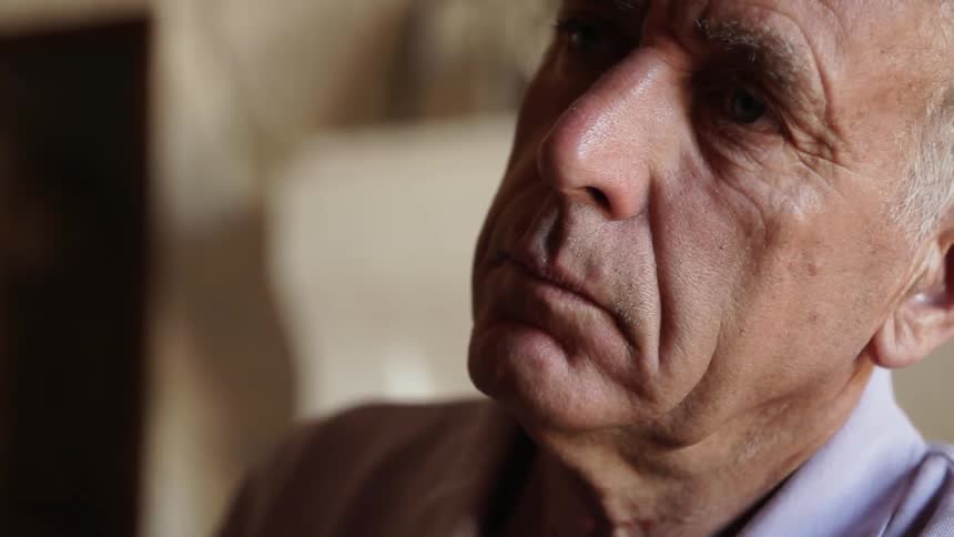 Elderly man sits and opens his eyes