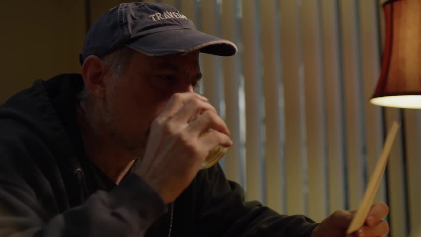 Man drinks whiskey while looking at photographs