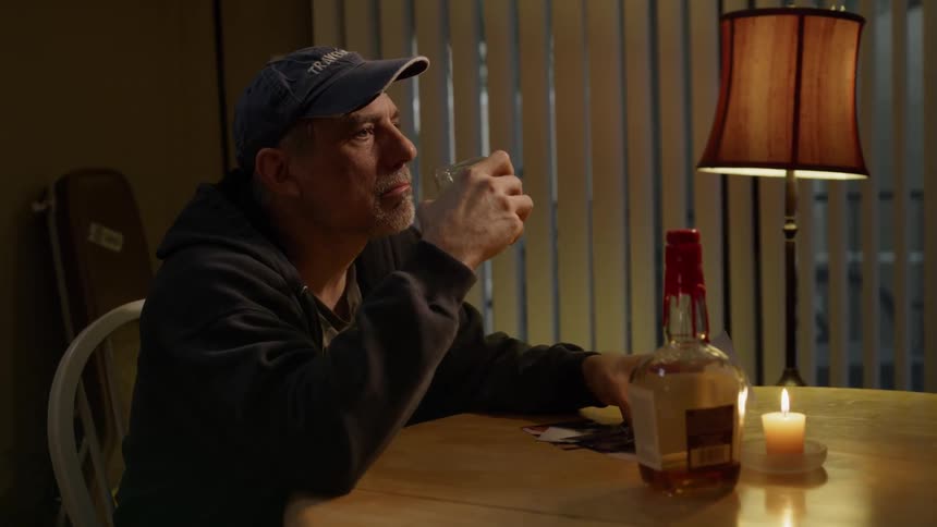 Man sits at a table drinking from a glass