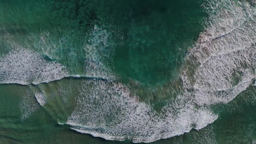 Waves are crashing and rolling ashore on a beach in daylight