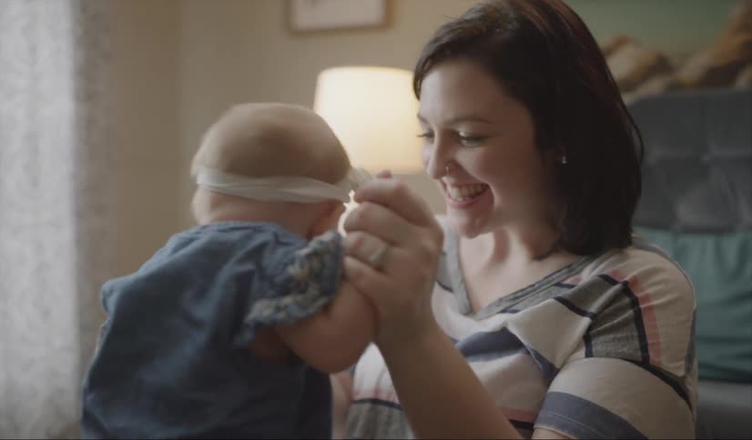 Woman sits on a bed playing with a baby