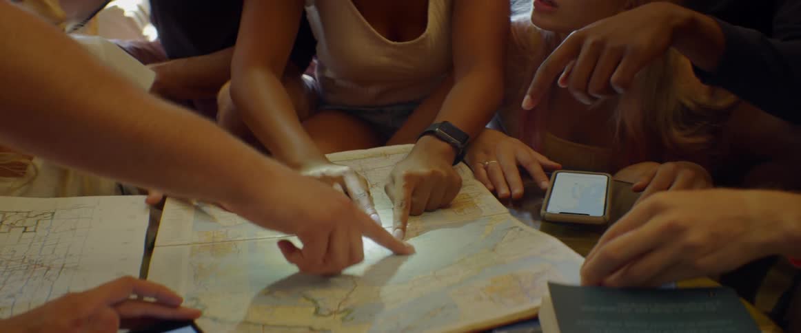 A group of people talk and point out locations on a map