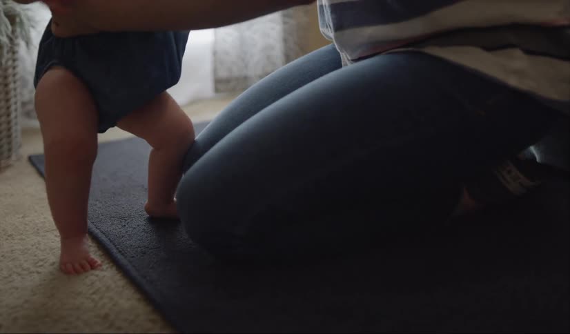 A woman holds a young baby as it balances