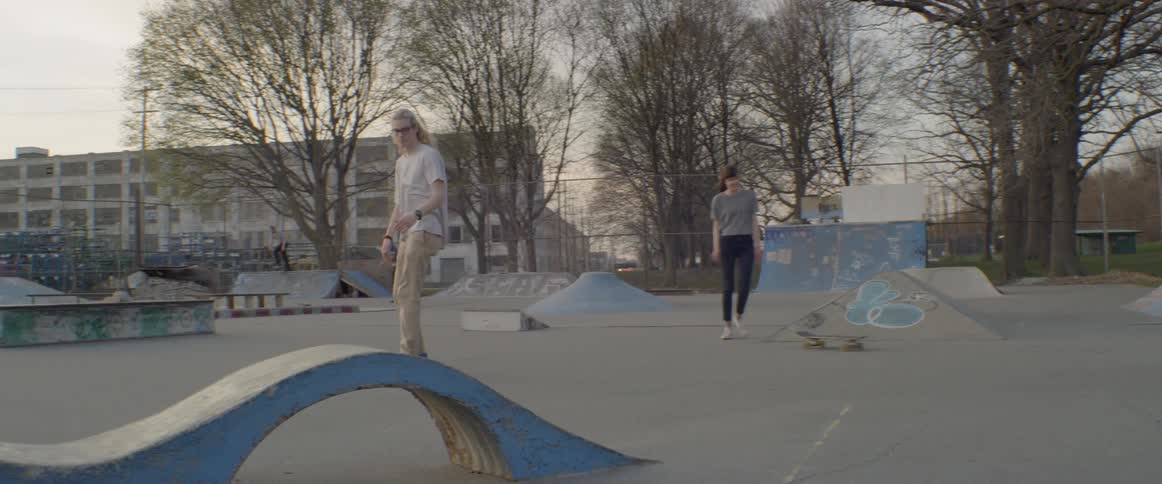 People skateboard in a skate park at sunset