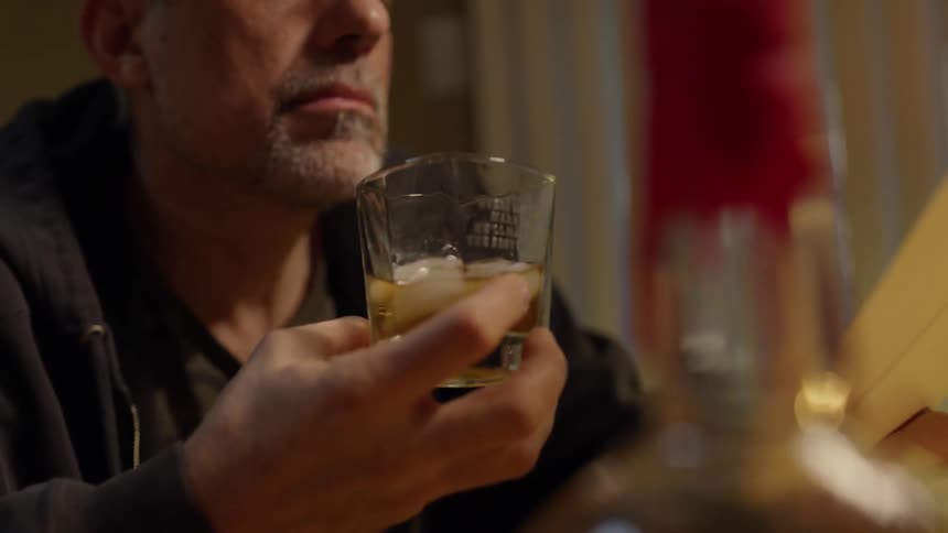 Man looks at photographs while drinking whiskey