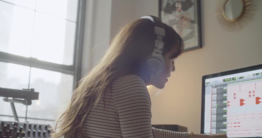 A woman sways around listening to music in front of the computer
