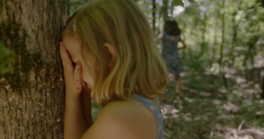 Little girls are playing hide and seek in forest