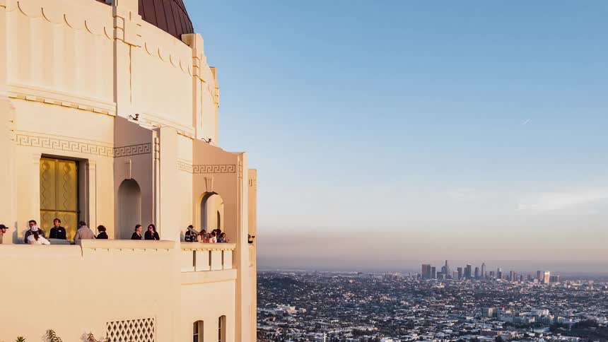 People walking on the balcony on a white building overlooking a city