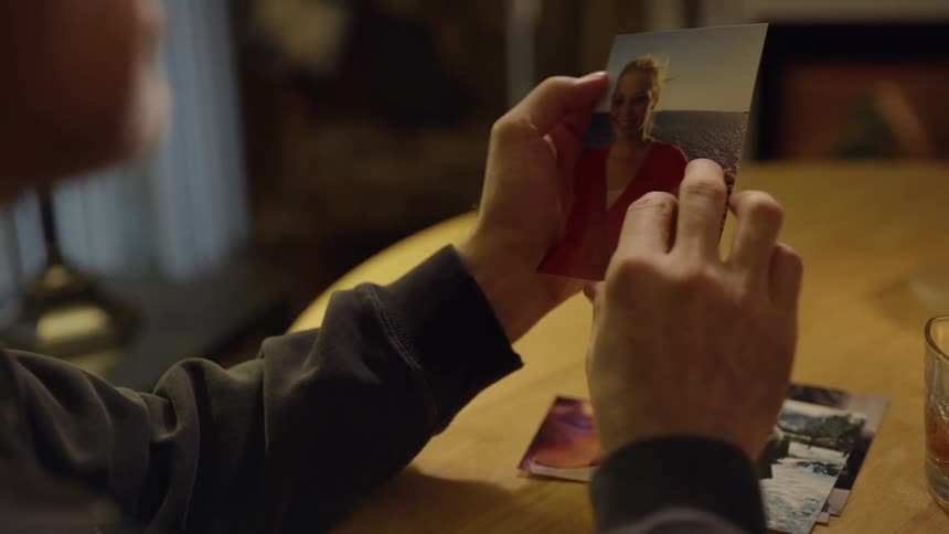 Man sitting at a table and looking at a photograph that he's holding