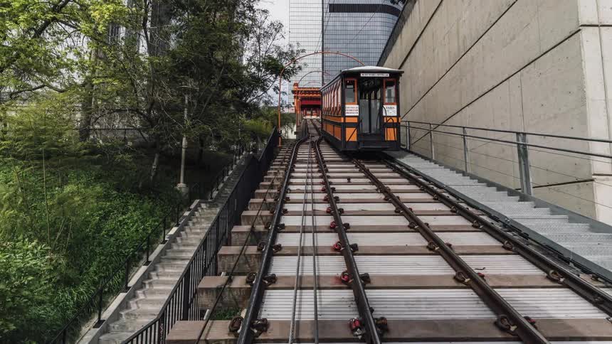 A commuter train is traveling on an elevated track in a city in daylight