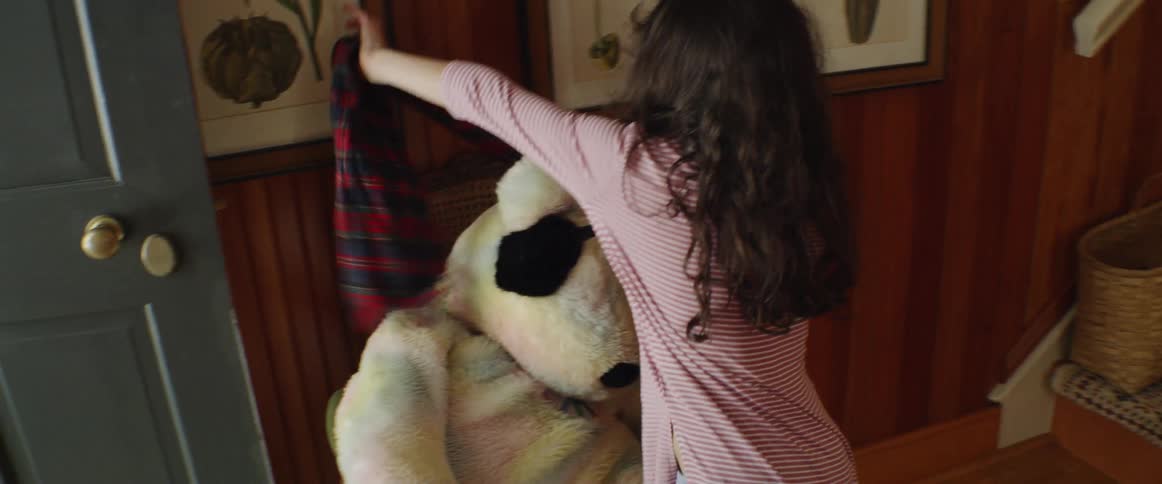 Girl wraps a scarf around a large teddy bear