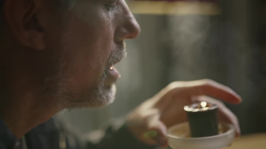 Man sitting at a table blows out a candle