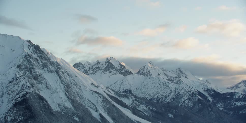 Clouds drift over snow covered mountains