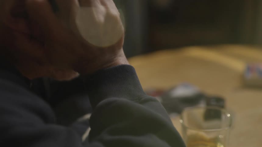 A person sits at a table with a drink