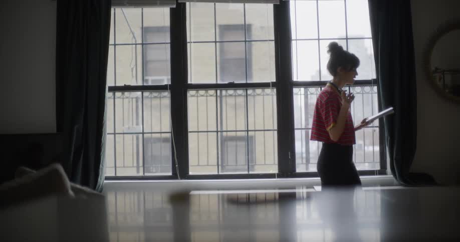 A woman paces back and forth studying a paper