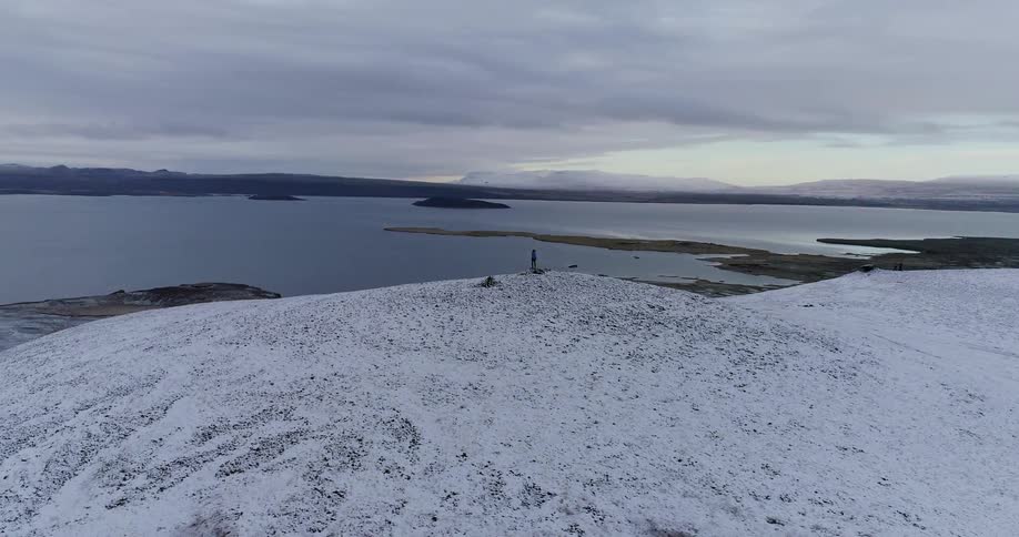 A person is standing on the hill by the shore