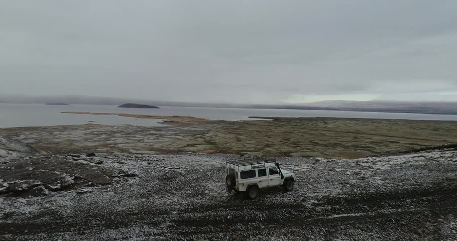 A white vehicle sits on a lonely road under a blue sky