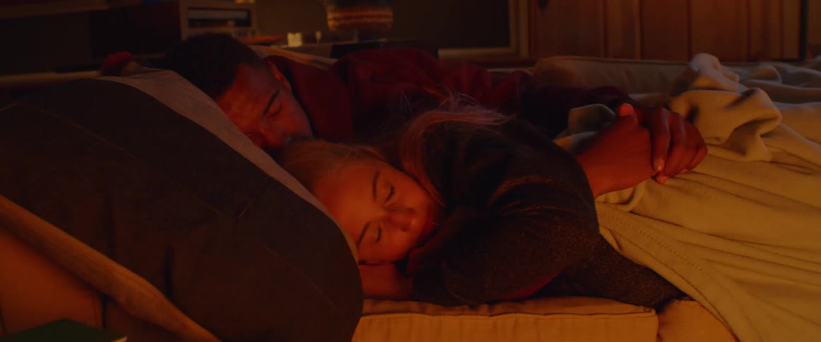 A man and woman sleep on a couch
