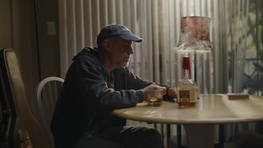A man blows out a candle while drinking whiskey