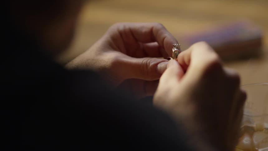 A person examines a ring at the table