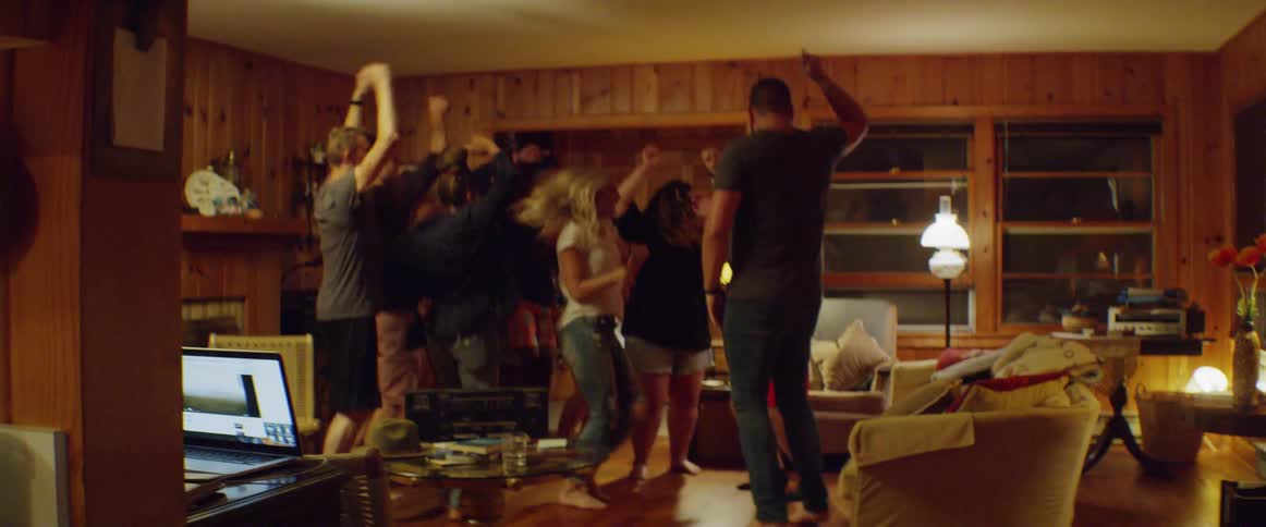 A group of friends jump and dance in a living room