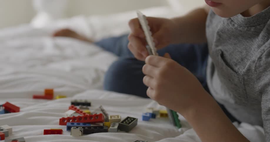 Boy plays with blocks on a bed