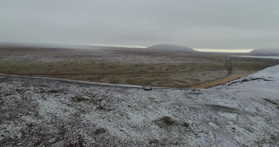 People exit a white vehicle on a snowy hill