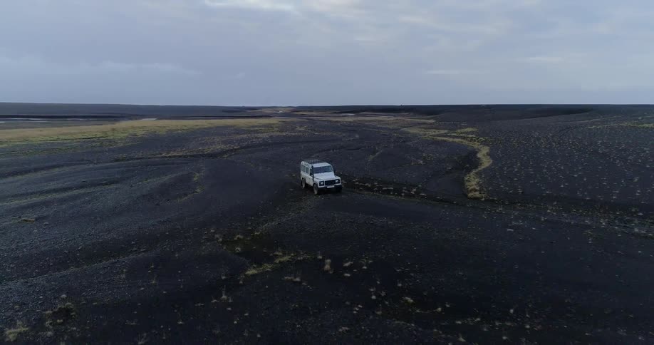 White jeep drives across flat plains
