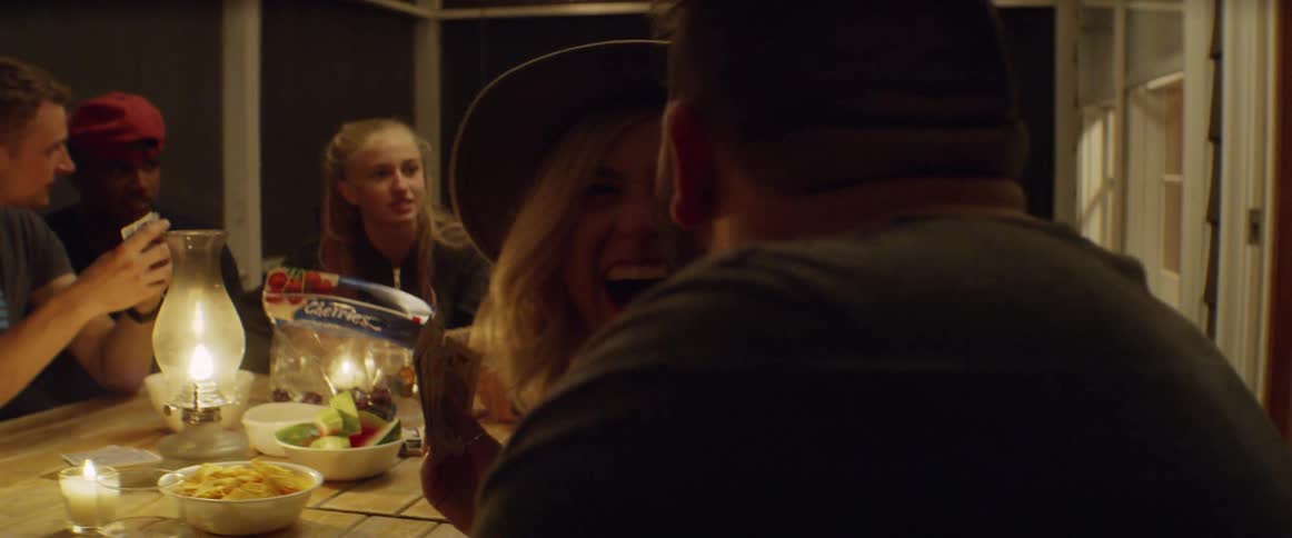 People sit around a candle lit table as they play cards