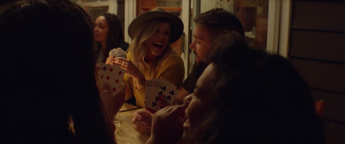 Group of people play cards as they talk and laugh