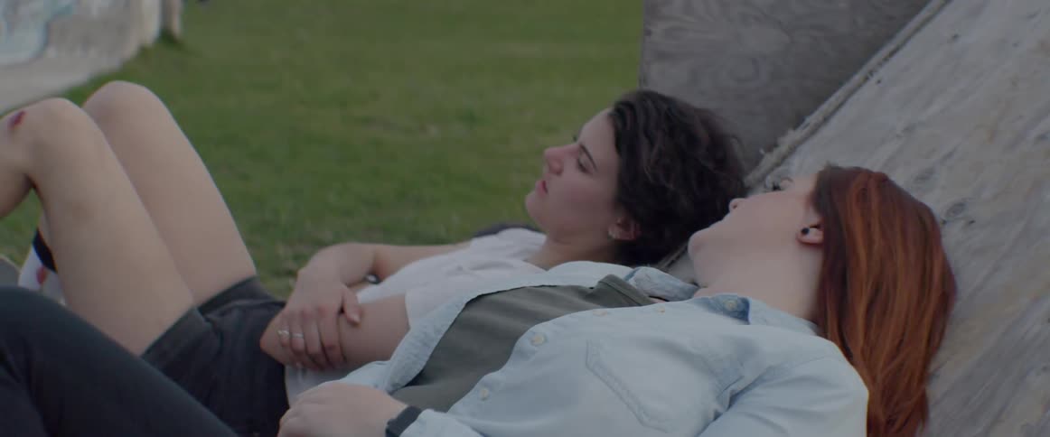 Two women are laying outside and talking