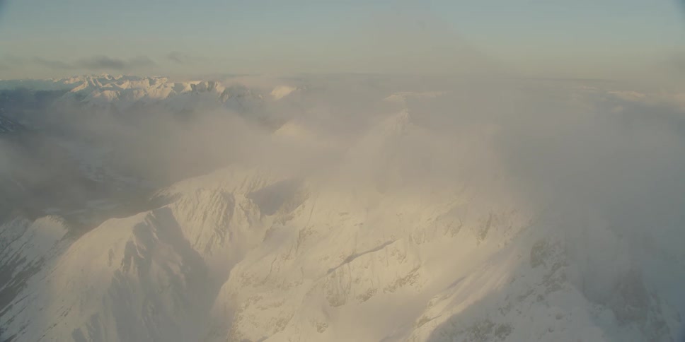 Clouds hover low over snowy mountains