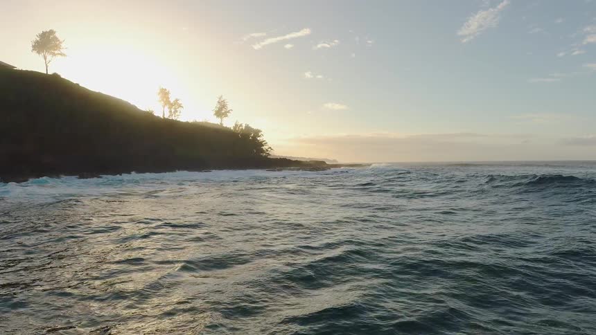 Ocean waves splash against the shore at sunset