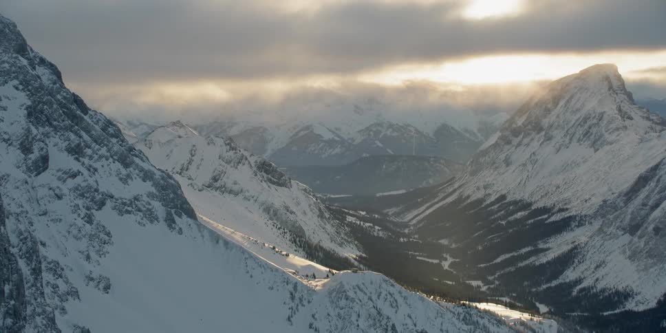 Clouds over snow covered peaks and mountain slopes