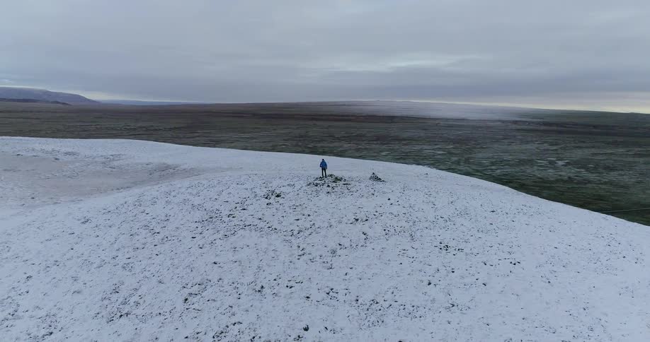 Man stands alone on a snow covered hill