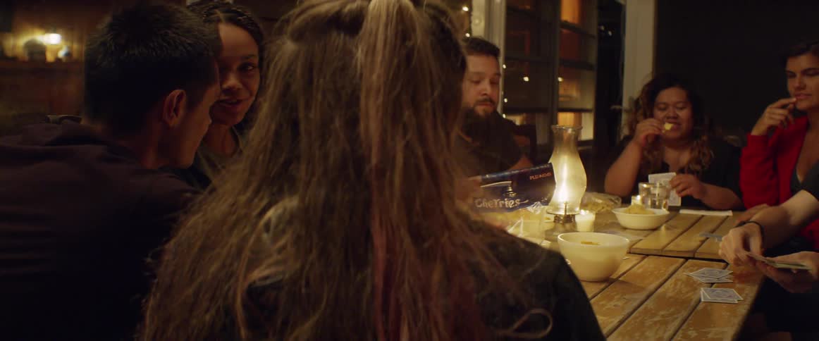 People play cards and eat snacks at a patio table