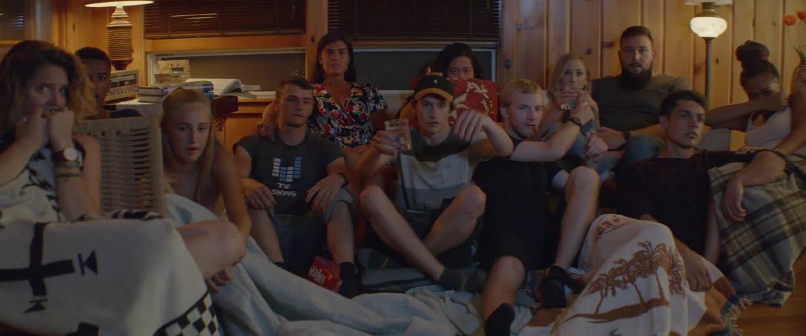 A person sits down with a group of people watching a movie