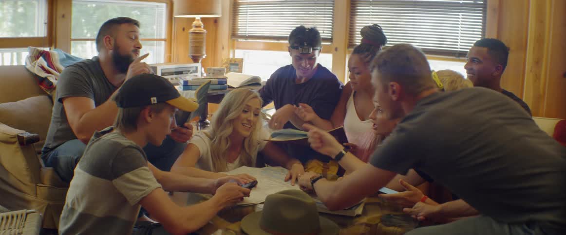 A group of people have a frantic gathered conversation